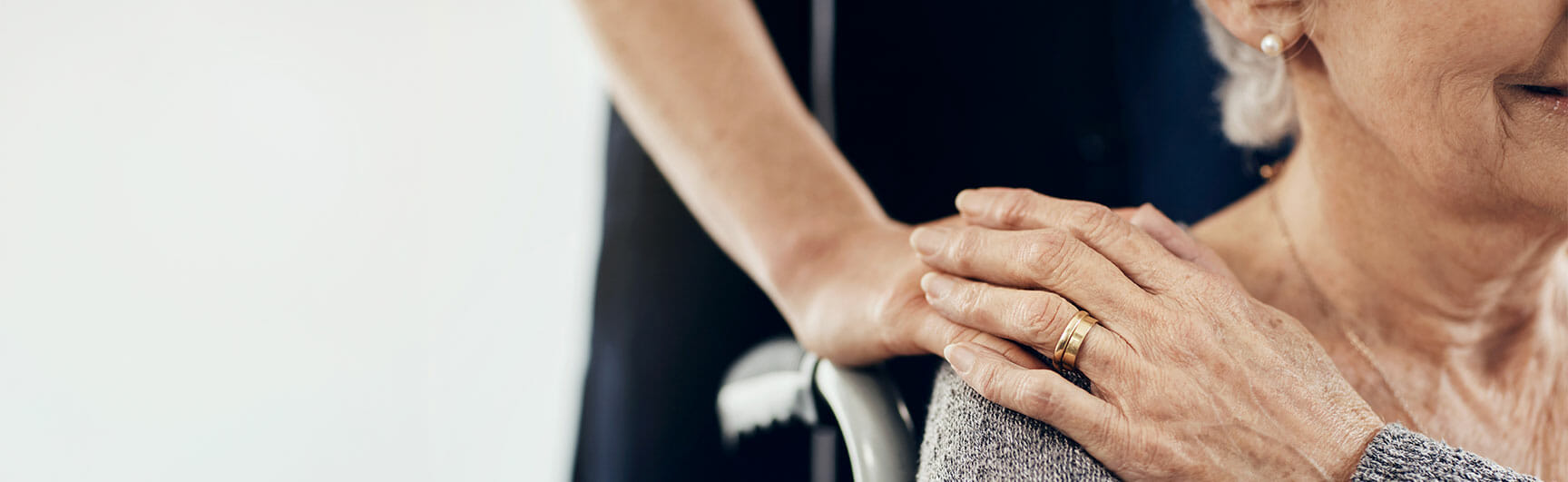 caretaker hand touching woman in wheelchair's hand