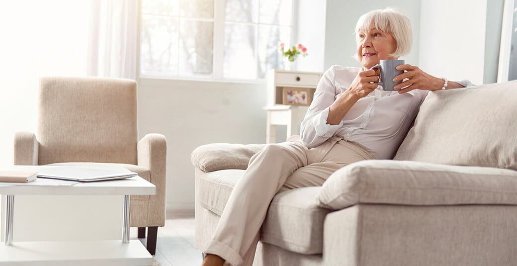 senior woman relaxing on couch with cup of tea