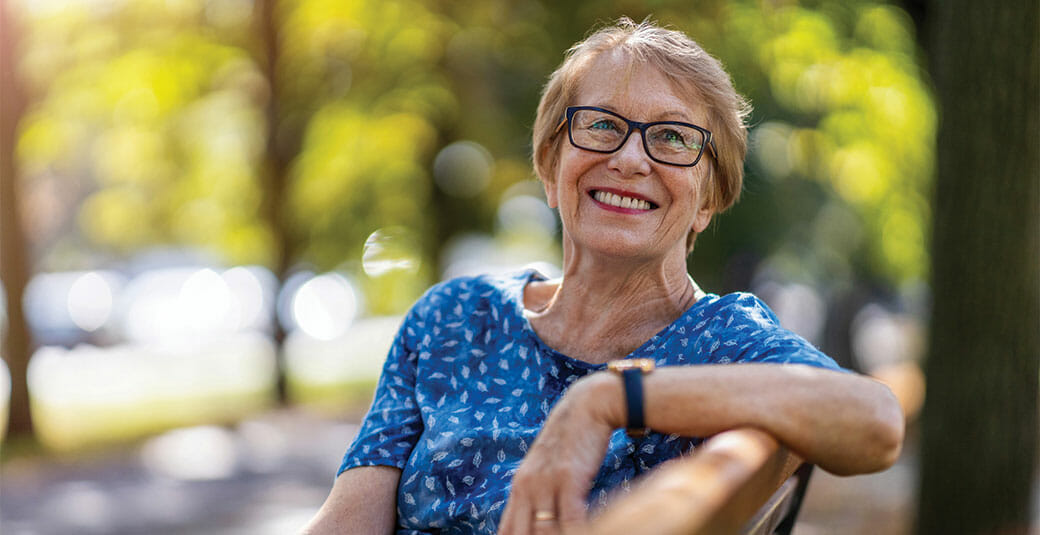 senior woman smiling on a bench at the park