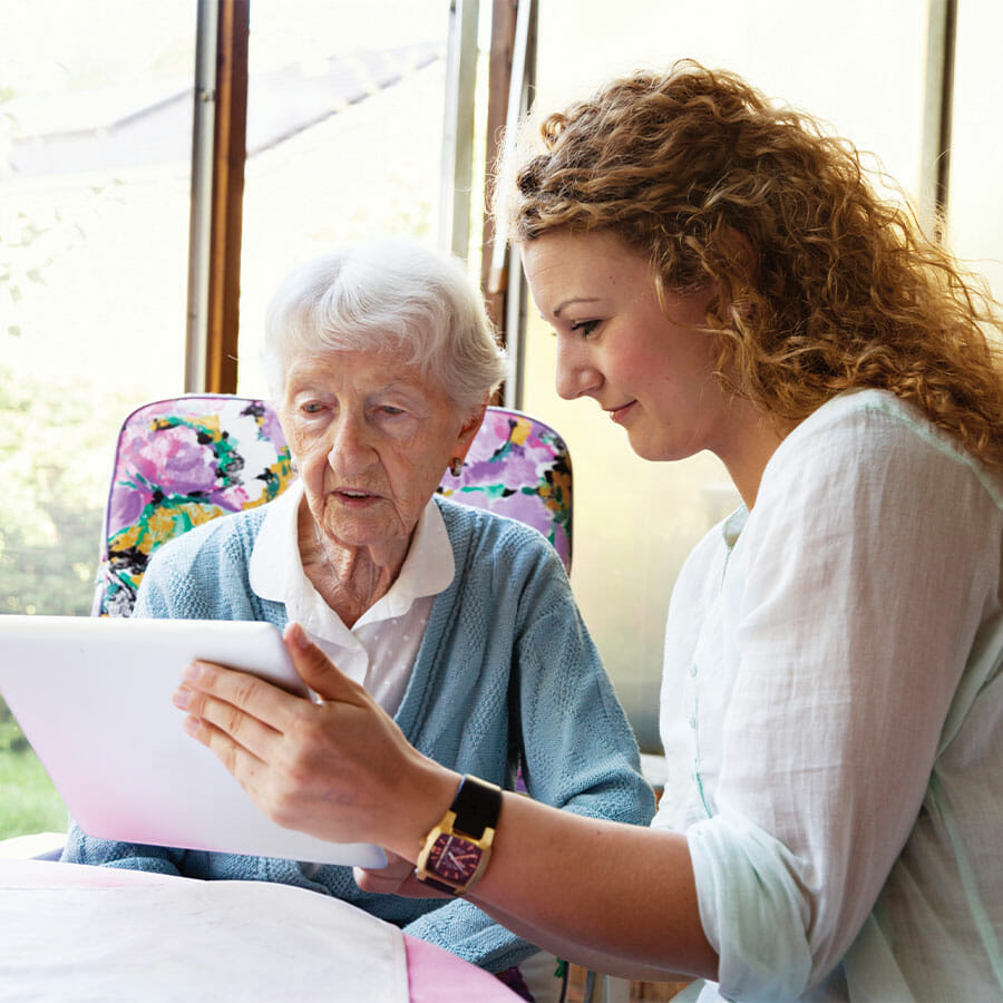 woman showing a senior lady a tablet