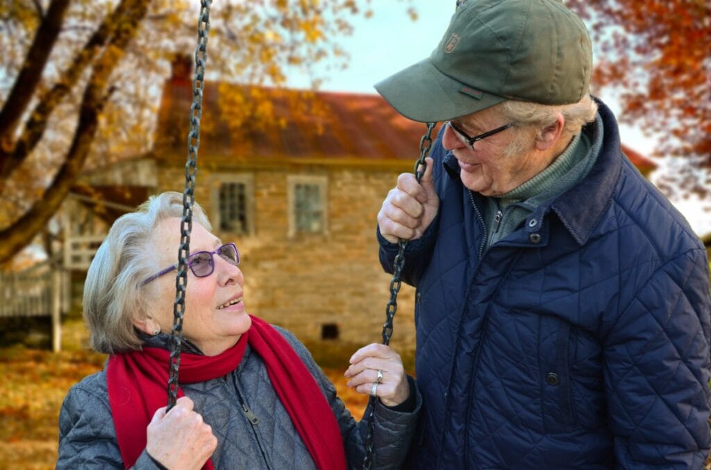 An elderly couple on a swing outdoors