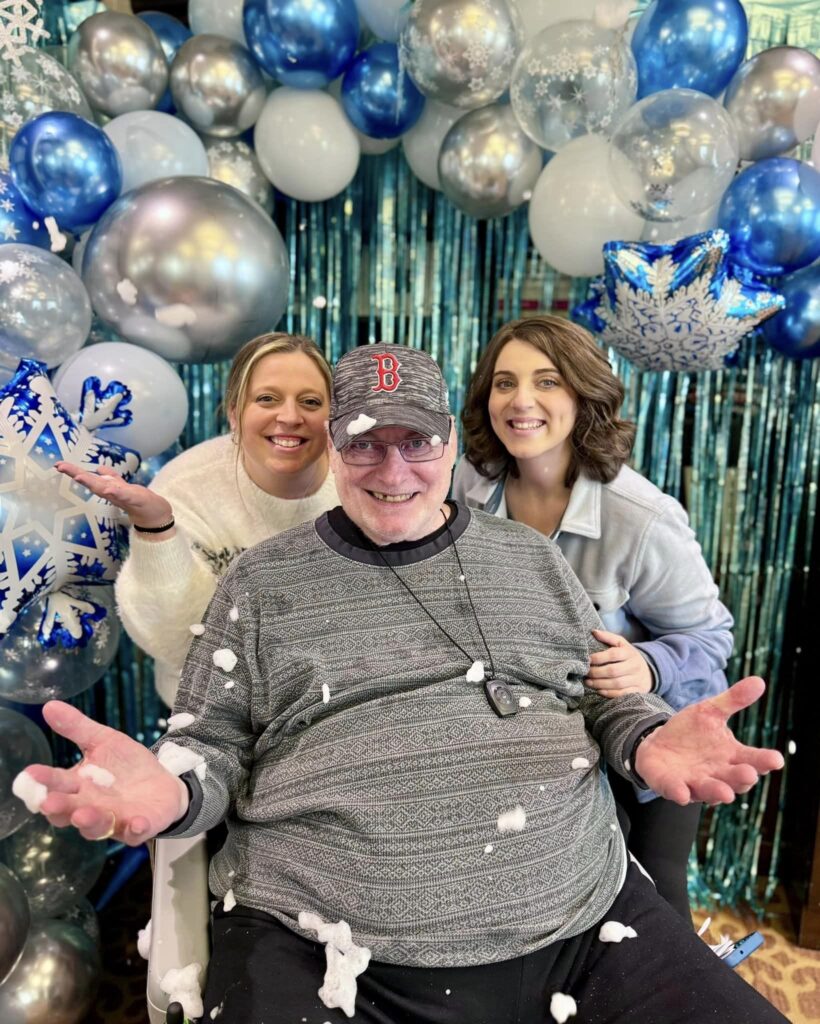 Smiling family with arms out in front of balloons