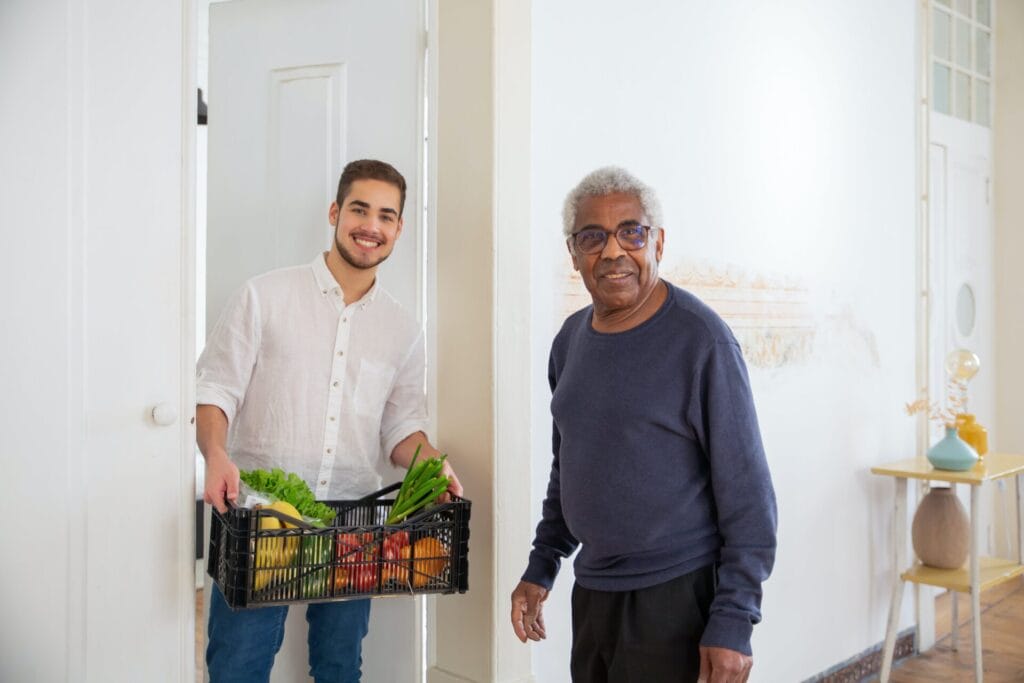 A younger person holding vegetables and helping an older man