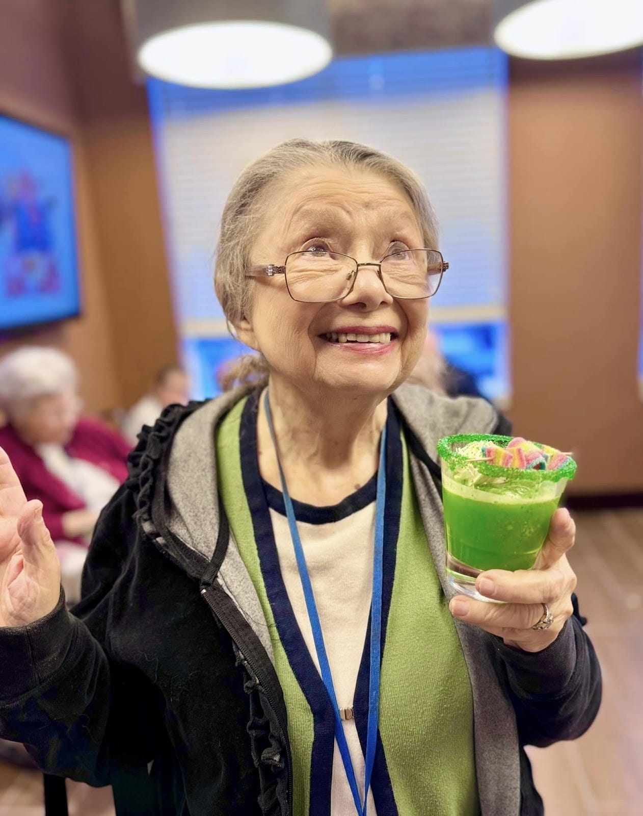 A senior citizen smiling and looking up while holding a special drink