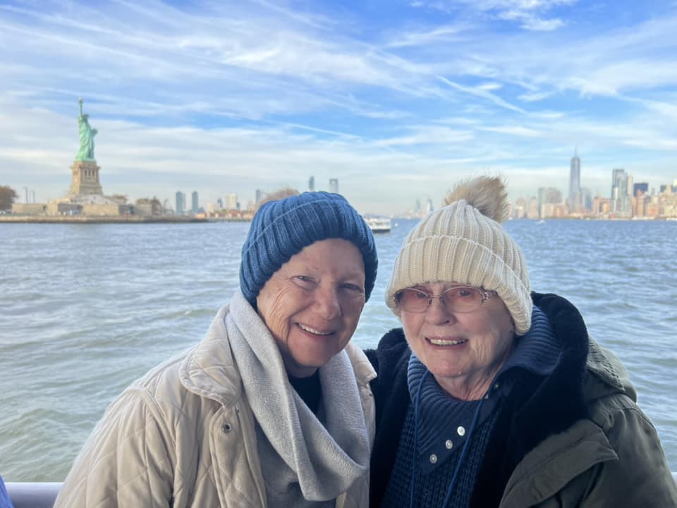 Senior citizens smiling with the Statue of Liberty in the background