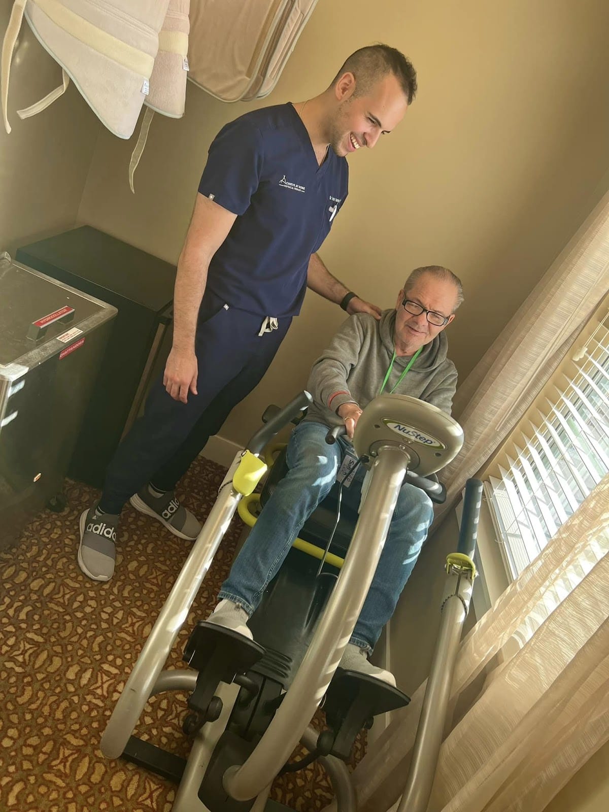 A physical therapist with a senior in a reclining bike