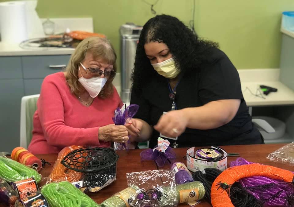 A senior citizen and assisted living facility staff member making crafts
