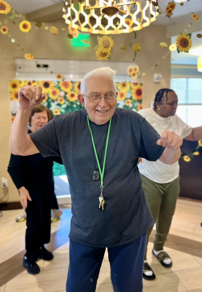 A smiling senior dancing with his hands in the air
