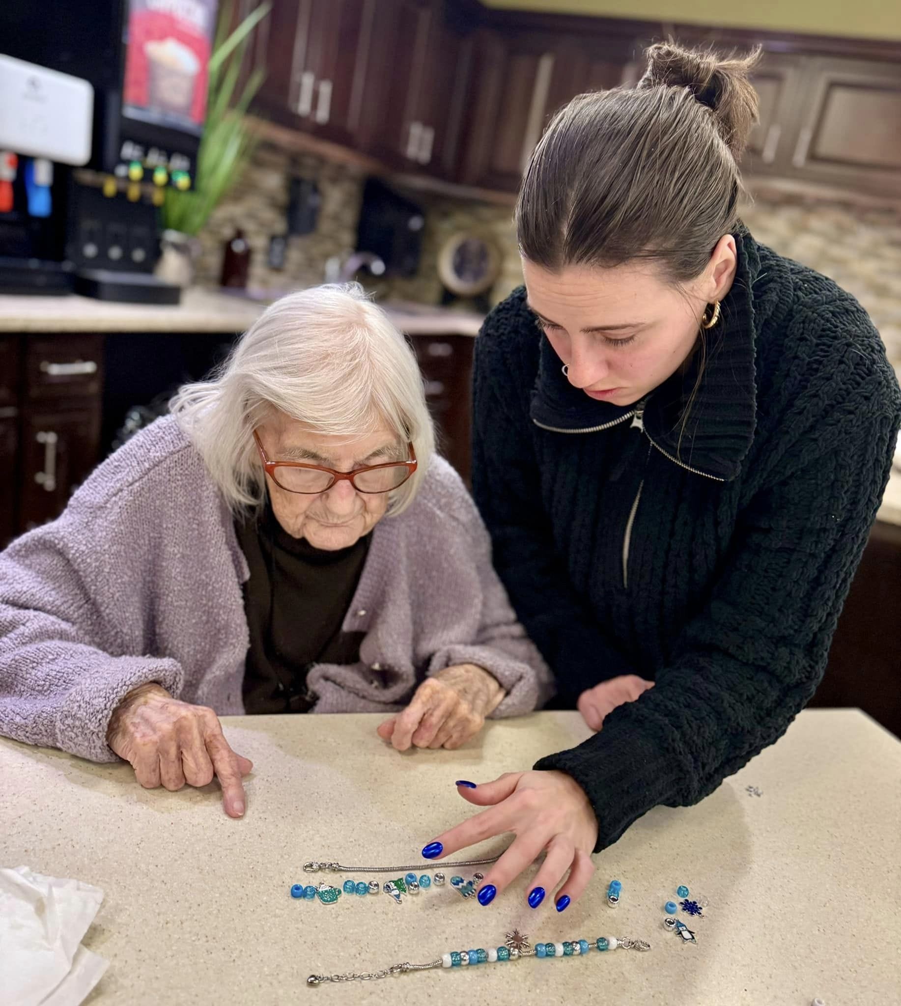 A woman and an elderly woman looking at a beaded necklace