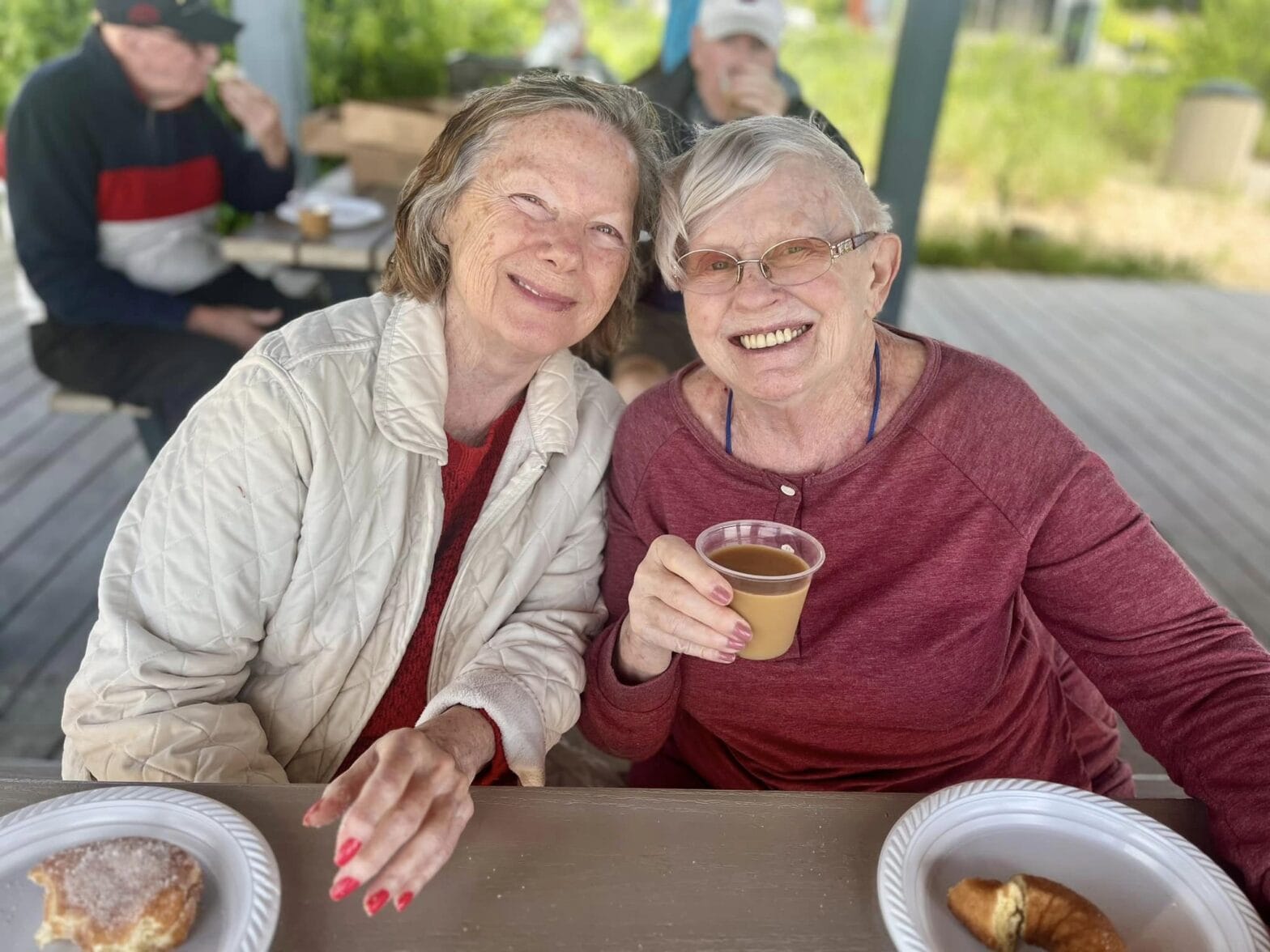 Two woman from a memory care facility eating and smiling
