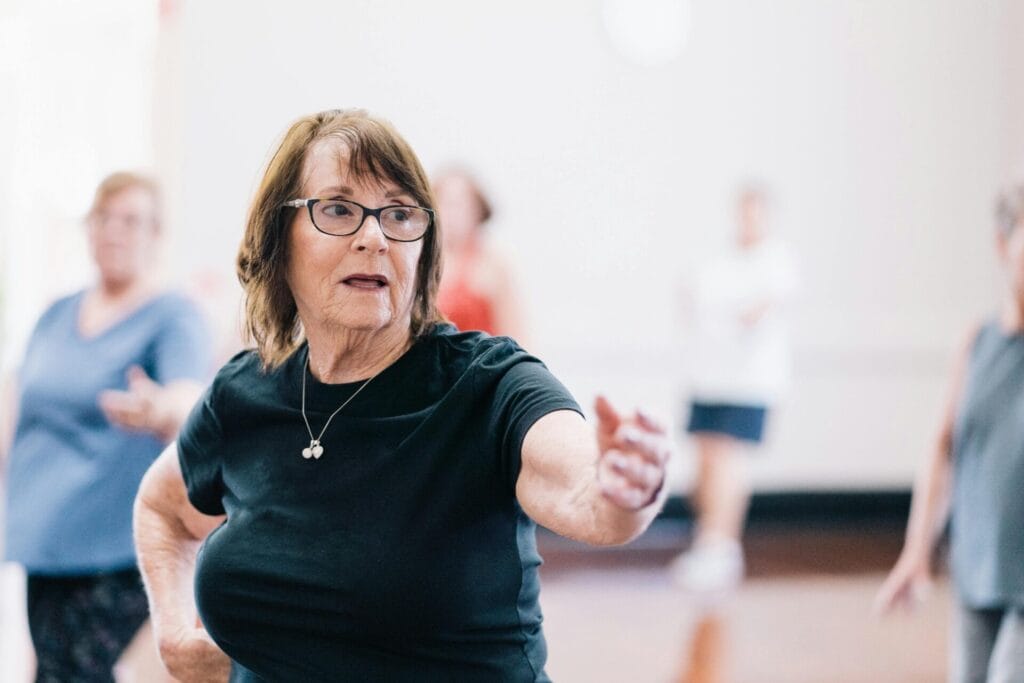 A woman with her arm extended in a group exercise class