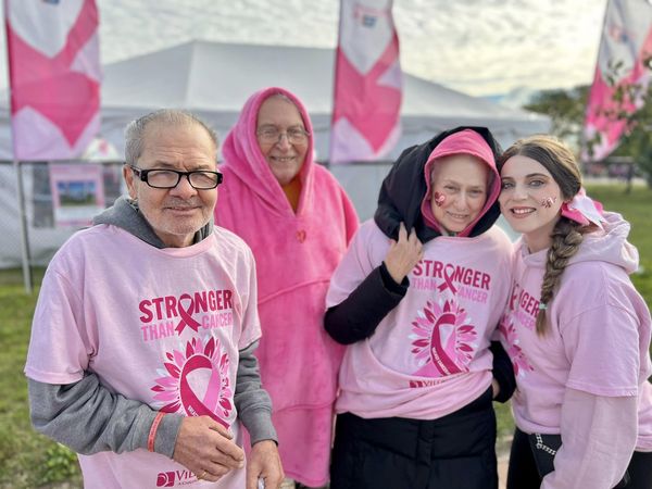 Assisted living residents wearing pink "Stronger than Cancer" t-shirts while standing outside