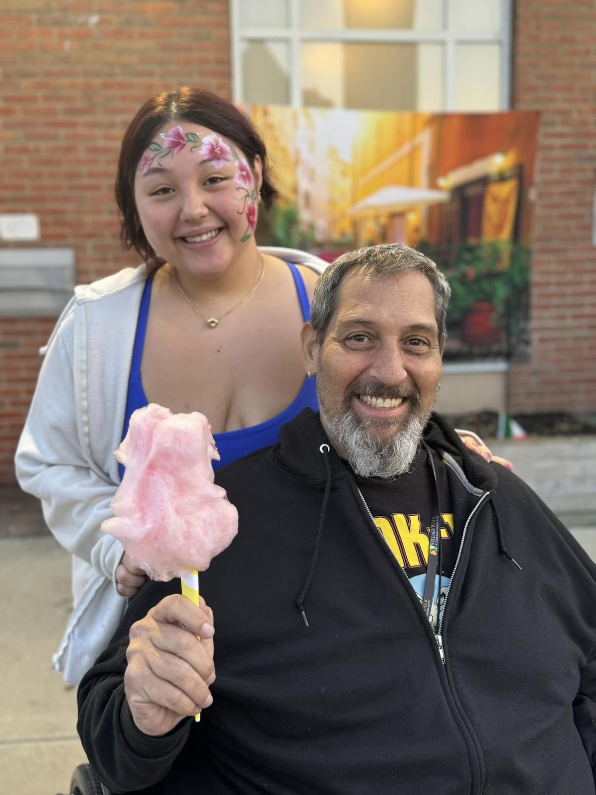 A young teenage woman and a man holding cotton candy and smiling