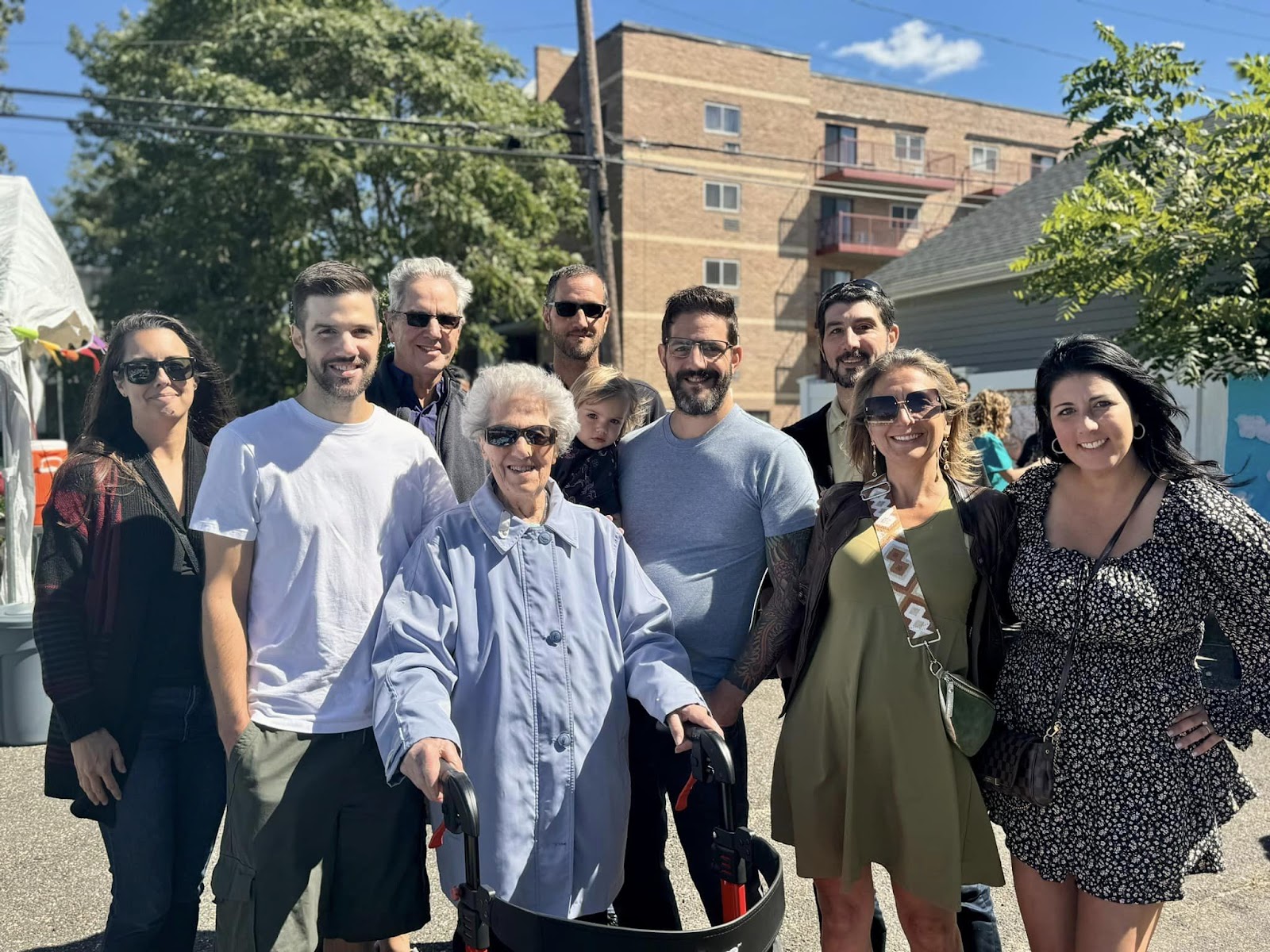 A family of 10 smiling outside on a sunny day