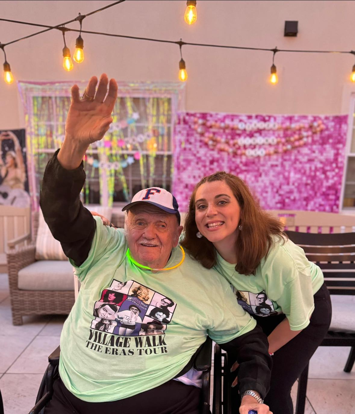 A dementia patient with his hands up and smiling with a caregiver