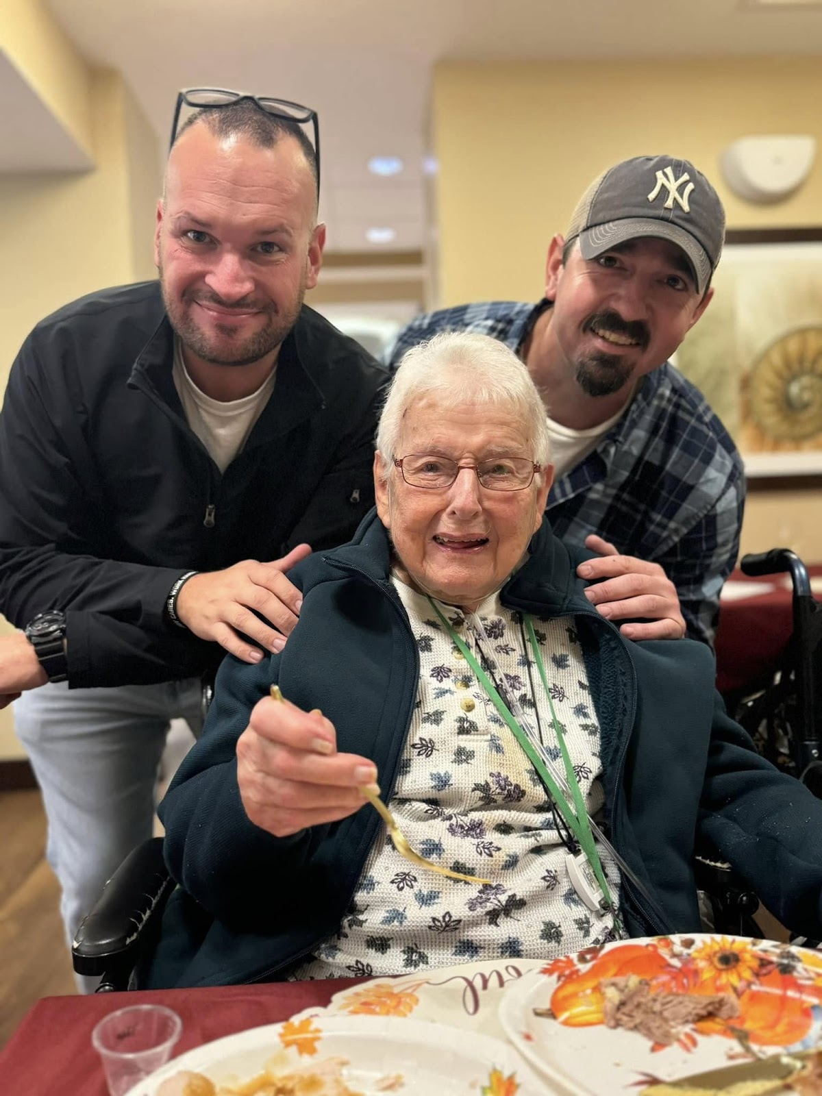 A picture of two young adults with their arms on the shoulders of an elderly woman 