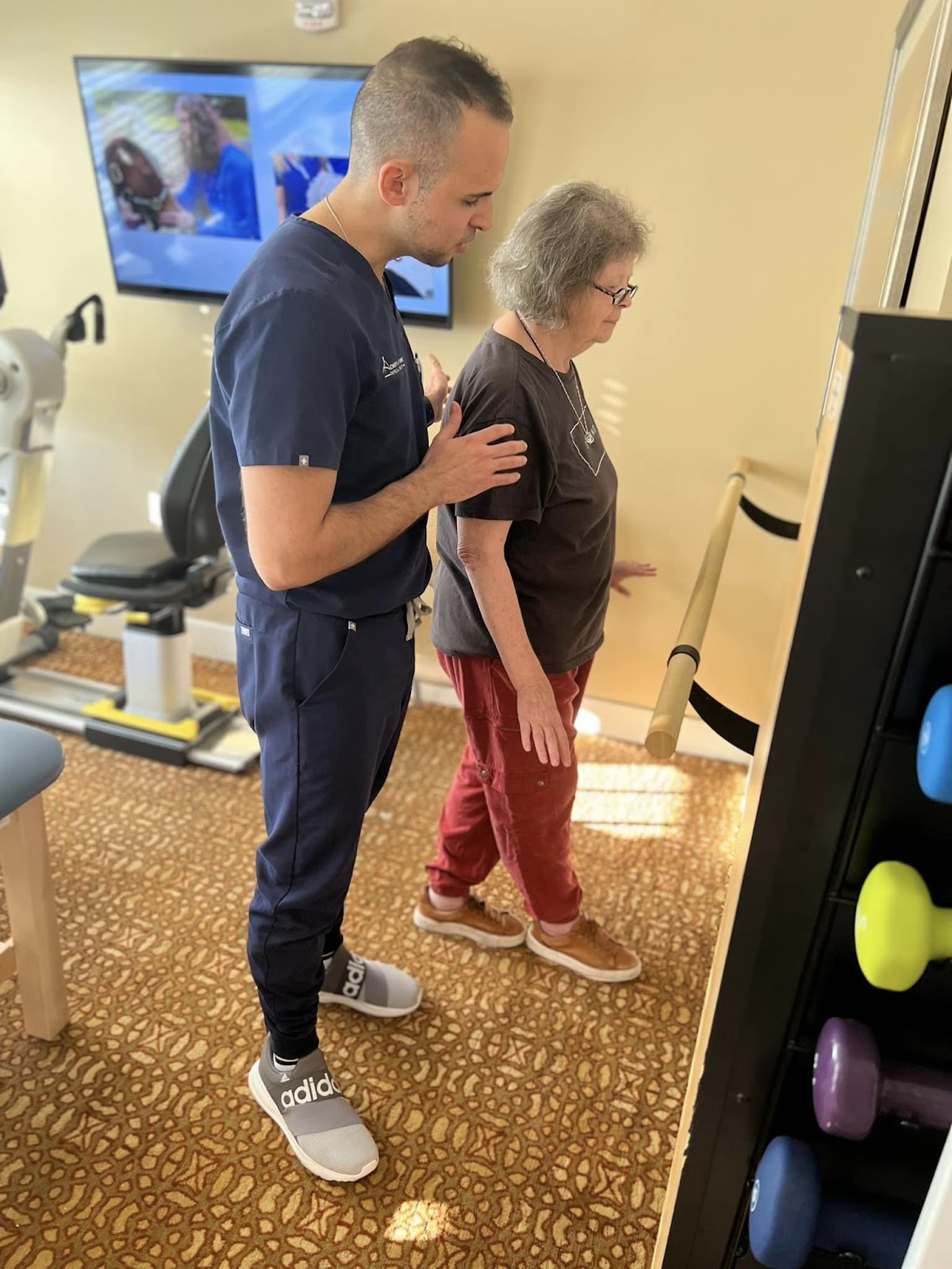 A physical therapist helping an elderly woman in an assisted living or nusing home walk