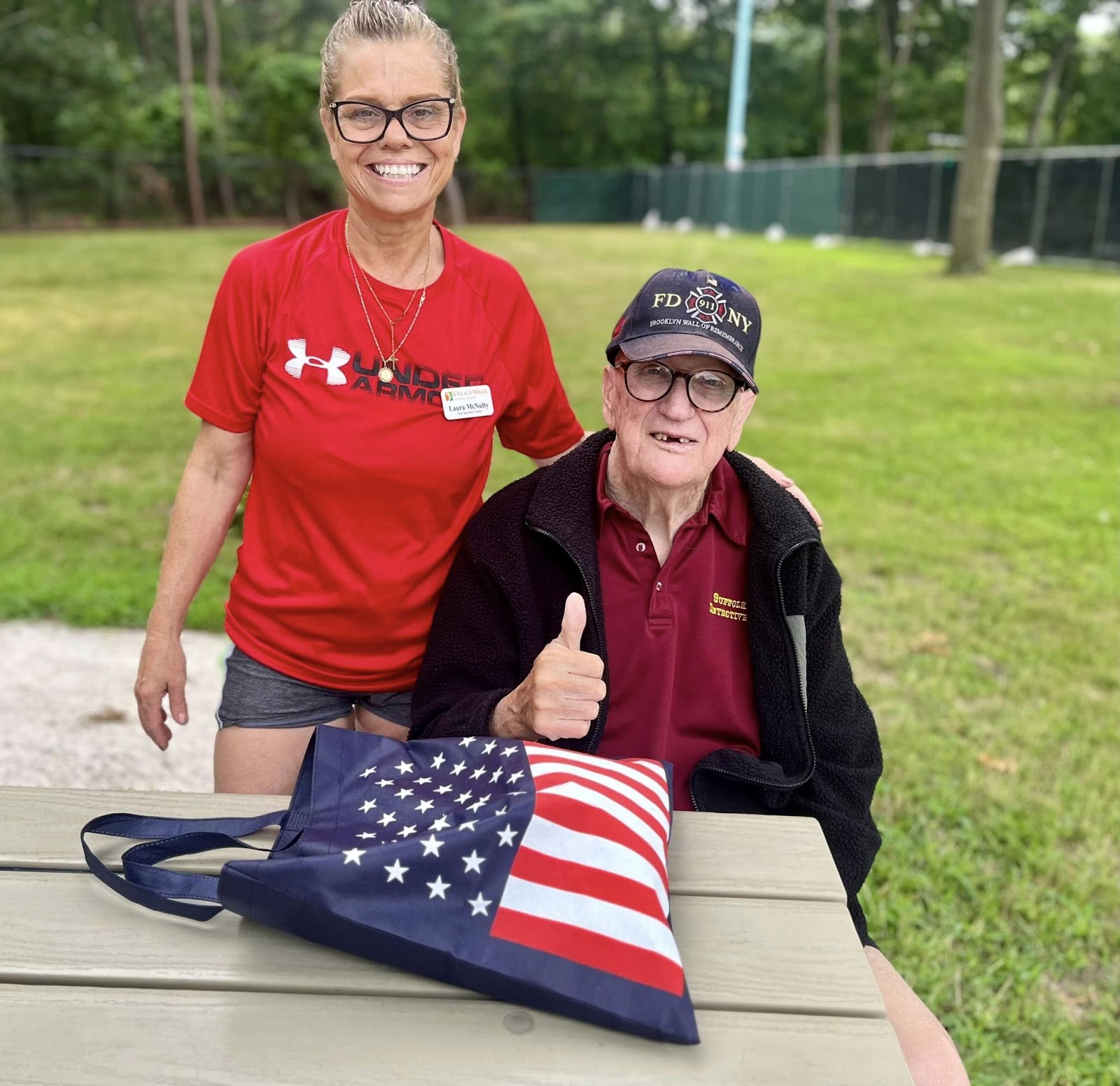 An assisted living aide smiling with a gentleman while standing outside