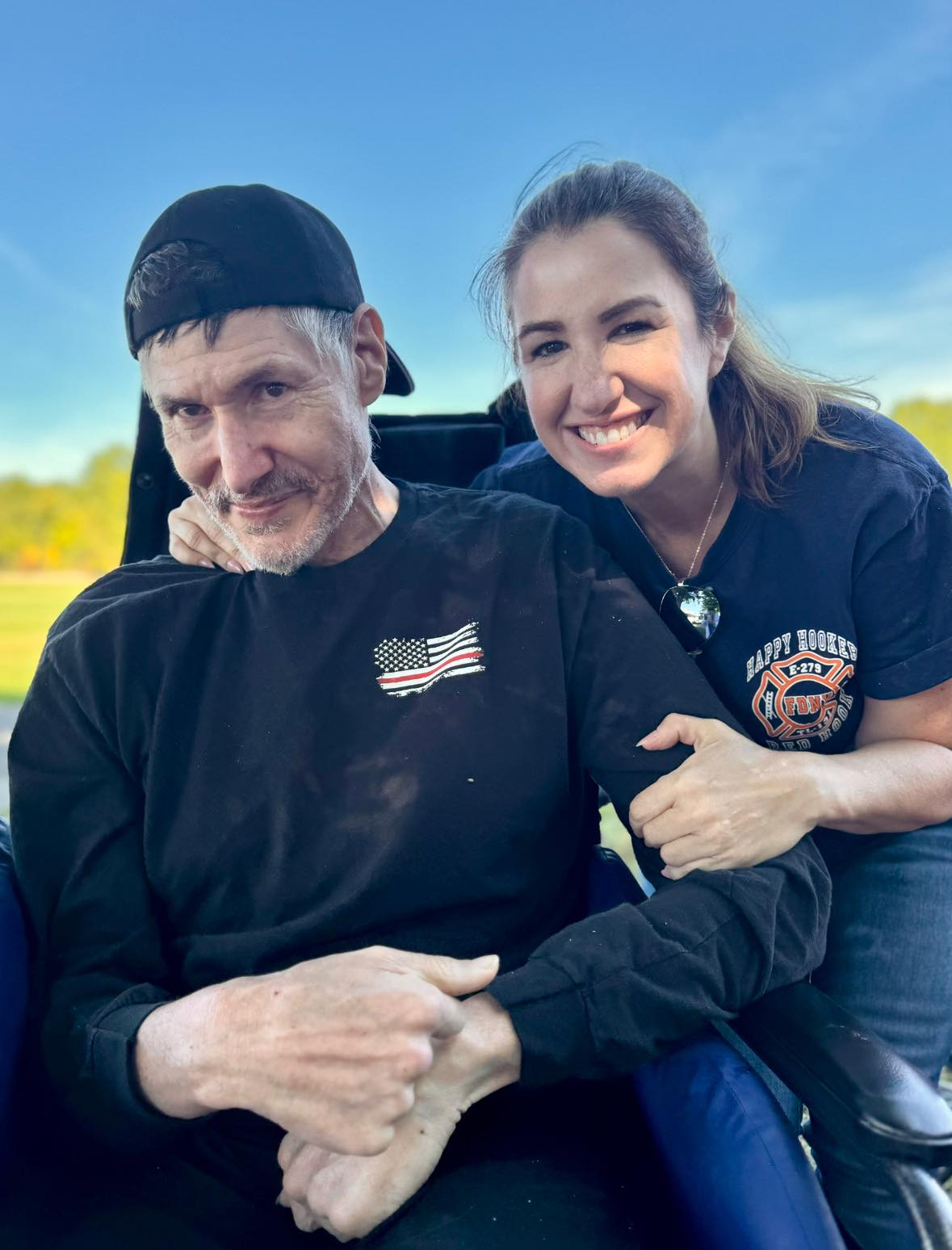 A young adult smiling with a man in a wheelchair.