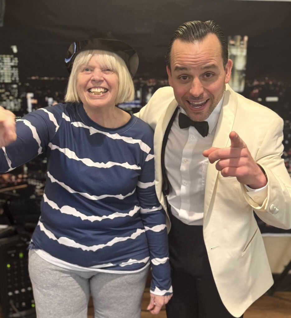 A man in a suit with an elderly woman smiling next to him