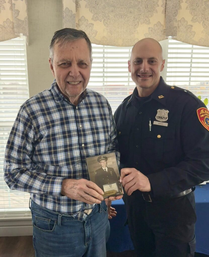 A picture of a man holding a picture of himself in armed services in years earlier