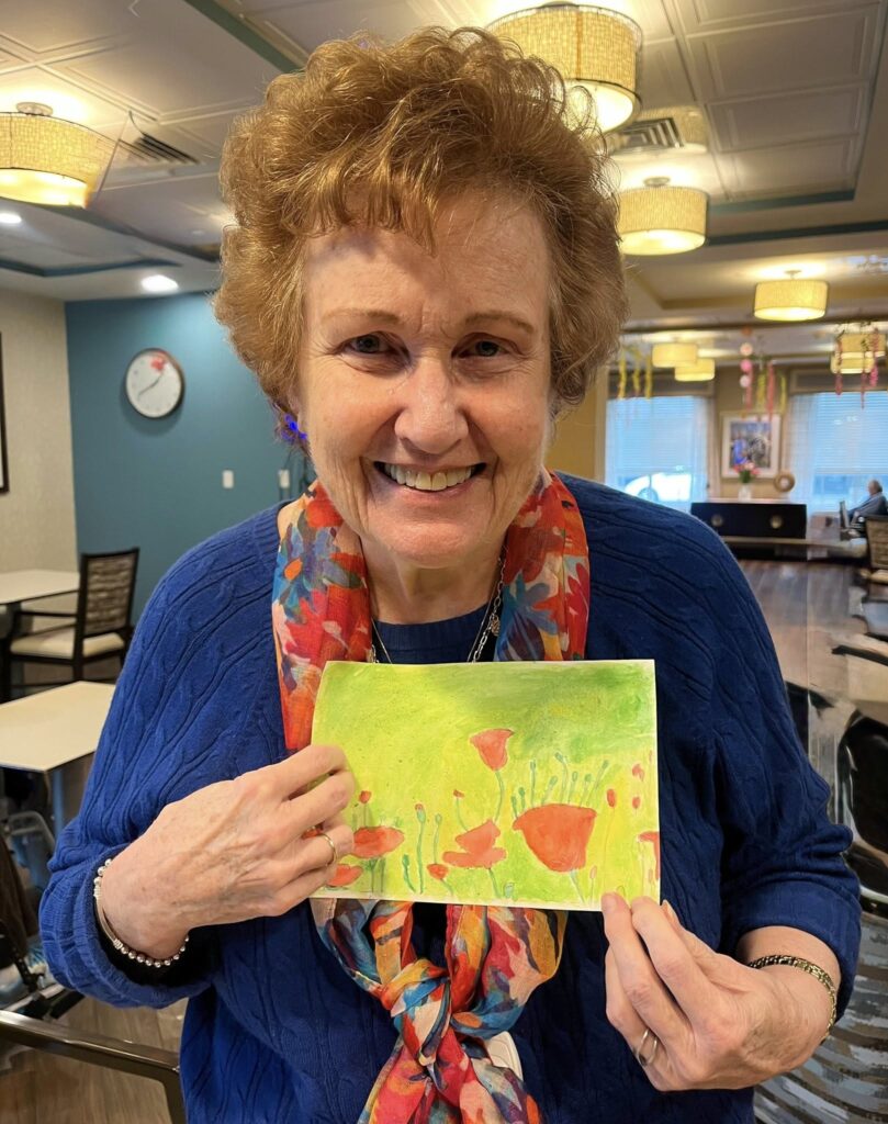 A woman smiling with an art piece she made