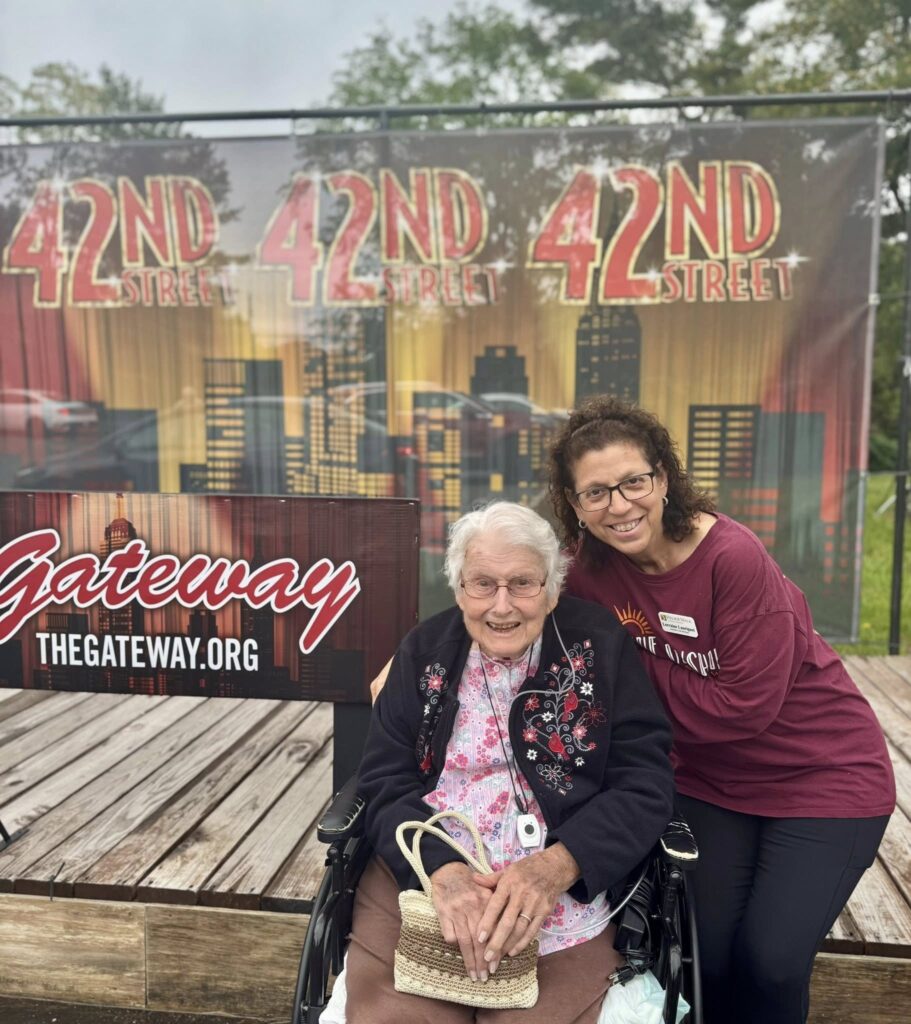 An assisted living staff member next to a outdoor banner